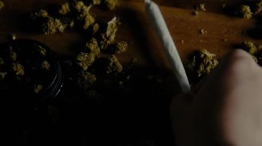 El gösterimi mekanı. Marihuana ahşap bir masada sığlaşıyor. Öğütücü, filtre kağıdı ve sigara. CBC, THC, indica veya sativa tomurcukları olan bir masada uyuşturucu.