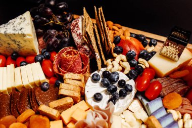 Peynir tabağı, peynir tahtası eti ve yiyecek. Sebze ve meyveli peynir ve çikolata, jambon ve salamlı ekmek. Parti için büyük bir atıştırmalık tahtası..