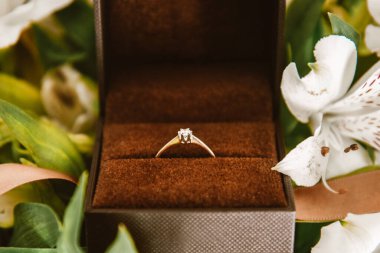 Wedding ring in a box close-up, gold ring with a diamond in flowers. Wedding, February 14, Valentine's Day, proposal for the bride, jewelry.