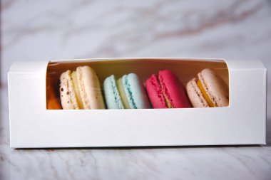 Macaron dessert, a box with colorful macarons lies on a marble style. Sweets, diet, gift for March 8 or February 14.