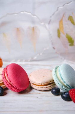 Macaron pink, orange and beige, blue on marble style. A beautiful and beautiful French dessert. Fruits and epoxy resin and flowers on the background.
