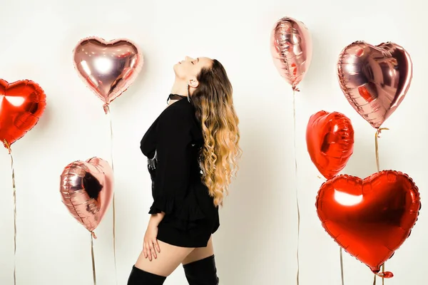 Gorgeous girl in a black dress and corset, in jewelry and raincoats with red balloons on a white background. Fashion and fashion, Valentine\'s Day