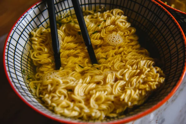 Instant pasta, Japanese and Chinese noodles. Ramen type soup in a plate with chopsticks, junk fast food. Quick-cooking pasta