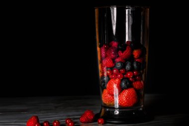 Fruit in a blender, mixer. Fruit cocktail and healthy food and drinks. Strawberry, raspberry, blueberry. Diet and vitamins for health, nutrition smoothie diet on a black background