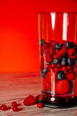Fruit in a blender, mixer. Fruit cocktail and healthy food and drinks. Strawberry, raspberry, blueberry. Diet and vitamins for health, diet smoothie nutrition on a red background