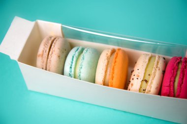Colorful macarons. Small French cakes. Sweet and colorful french macarons in a box on a blue background. Gift for Valentine's Day