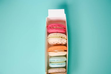 Colorful macarons. Small French cakes. Sweet and colorful french macarons in a box on a blue background. Gift for Valentine's Day