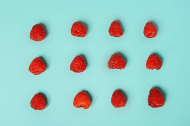 Raspberry pattern on the blue color of the lagoon. Fruits and healthy food, trendy photo