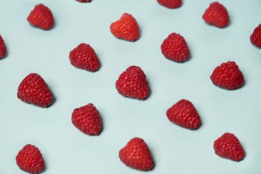 Raspberry pattern on the blue color of the lagoon. Fruits and healthy food, trendy photo