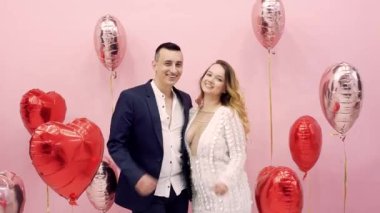 Sevgililer Günü 14 Şubat 'ı kutluyor, aşkım. Balonların arkasında öpüşen kadın ve erkek kırmızı kalpler, romantik randevu, sarılma, tatlı