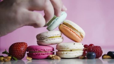 Renkli kurabiyeler. Küçük Fransız kekleri. Tatlı, taze böğürtlenli, ahududulu, yaban mersinli, fındıklı ve çilekli bir sürü lezzetli badem kurabiyesi pembe arka planda. Karanlıktan aydınlığa geçiş.