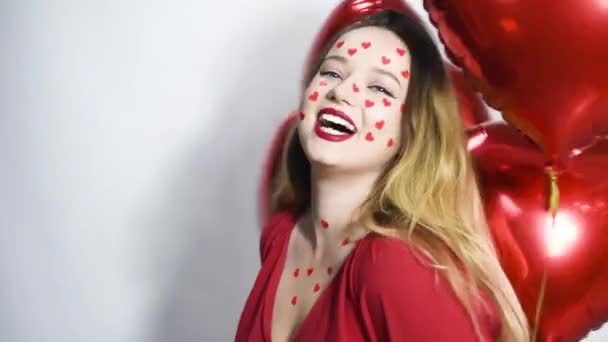 Yüzünde Kalp Etiketi Olan Bir Kadın Kırmızı Balonların Arka Planında — Stok video