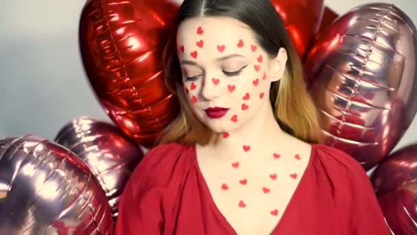 Yüzünde Kalp Etiketi Olan Bir Kadın Kırmızı Balonların Arka Planında — Stok video