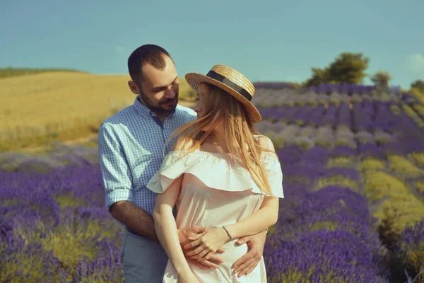 Couple in love kissing in a lavender field. Romance and travel, love. A pretty girl in a dress and a straw hat, and a man.