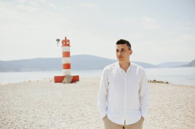 Beyaz gömlekli bir adam sahil boyunca yürür. Dağların arka planına karşı duran adam ve deniz kızıl fenere gider. Dinlen ve seyahat et.