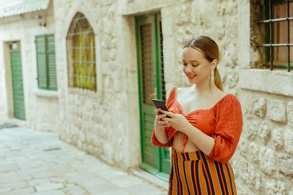 老城区的女人摆姿势漂亮的时髦女孩 手里拿着智能手机 网上约会 在欧洲各地旅行 — 图库照片