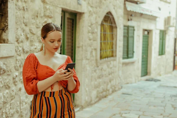 老城区的女人摆姿势漂亮的时髦女孩 手里拿着智能手机 网上约会 在欧洲各地旅行 — 图库照片