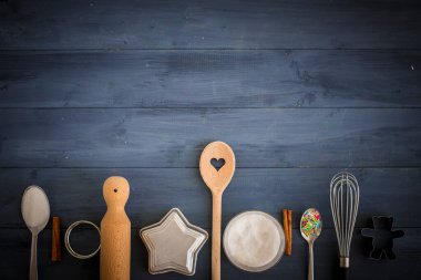 Baking tools and ingredients header, background with copy space. Blue wooden table with sugar, spoons, whisk and cookie cutters. homemade dessert concept.