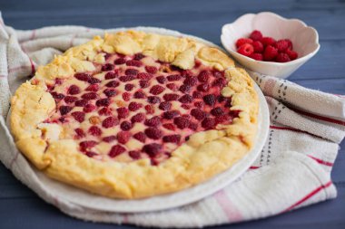 Ev yapımı ahududu pastası ya da mavi ahşap bir masa üzerinde beyaz bir bez, yanında taze böğürtlen, kenar manzaralı.