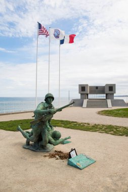 Omaha plajı anısına bir asker heykeli tüfek taşıyor ve Normandiya Çıkarması sırasında arkadaşına yardım ediyor. Vierville sur Mer, Normandiya, Fransa. Dikey çekim.