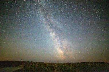 Gece gökyüzü ve samanyolu çekirdeği kır manzarasında yeşil çimlerin üzerinde. Brittany, Fransa. Kopyalama alanı olan arkaplan.