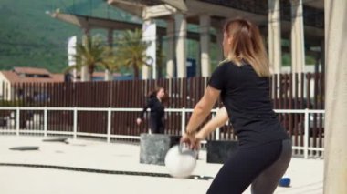 Kettlebell 'le çömelme hareketi yapan atletik bir kadın, kavramsal kavram ve ağırlık çanlarıyla egzersiz yapan bir kadın.