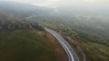 İnsansız hava aracı güz sabahı dağ yolu. Yoğun sabah sisiyle kaplı yalnız arabalarla.