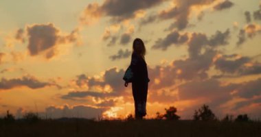 Kırmızı günbatımında ya da kırmızı gündoğumunda ulusal elbiseli romantik sarışın kız silueti. Köy kavramı