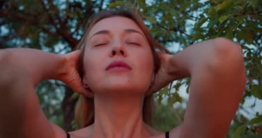 Güzel romantik kadın, güzel sarışın manken kamerada hareket ediyor, batan güneşin ışınlarında gülümsüyor.