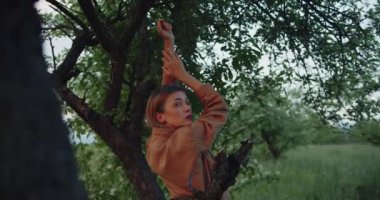 Romantik bir kadın, kahverengi gömlekli güzel bir kadın model, elma bahçesindeki bir çayırda poz veriyor.