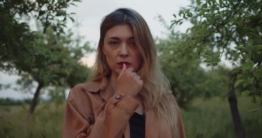 Romantik bir kadın, kahverengi gömlekli güzel bir bayan model çayırda duruyor ve kameraya bakıyor.