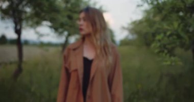 Romantik kadın, kahverengi gömlekli güzel kadın model ağaçların dallarında dikilip kameraya bakıyor.