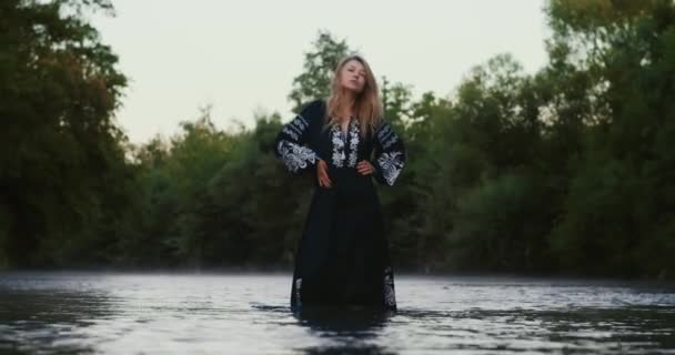 ロマンチックなブロンドの女の子は 民族衣装の女性は山の川の朝の霧に包まれて立っている — ストック動画