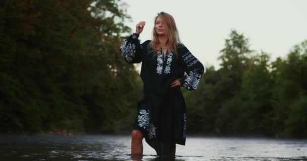 一个金发碧眼的浪漫姑娘 一个身穿民族服装的女人站在山河边 笼罩在晨雾之中 — 图库视频影像