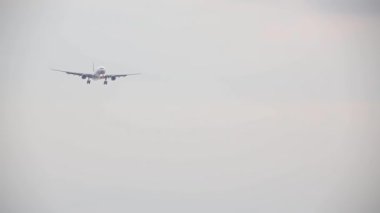 Beyaz arka planda yalnız bir uçak inişe hazırlanıyor.