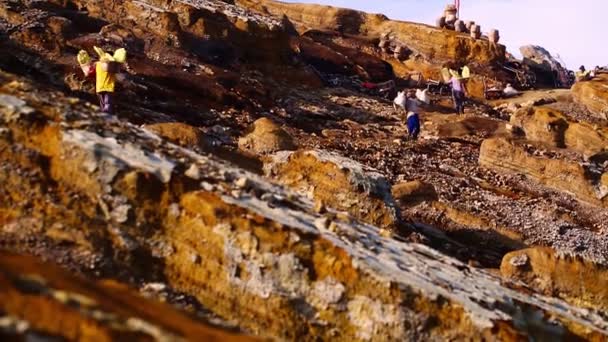 東ジャワの硫黄鉱山労働者は危険で勤勉で 活発な火山で重い硫黄のバスケットを運ぶ — ストック動画