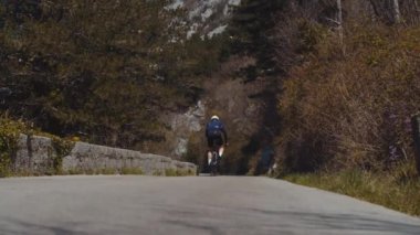 Bisikletçi yüksek dağ duvarları arasında bir dağ yolunda gidiyor.
