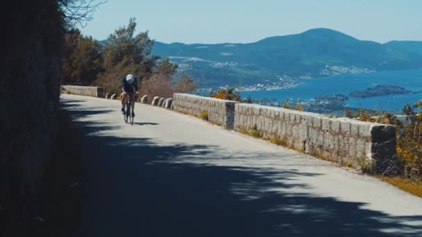 高い山と海の間の山道にサイクリストの乗り物 モンテネグロの道路上の唯一のスポーツマンサイクリング — ストック動画