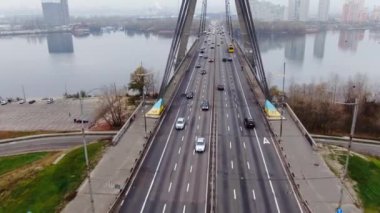 İnsansız hava aracı köprünün çelik halat iskelelerinde uçuyor. Araba trafiğine bakıyor.