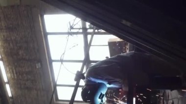 Dikey kaynakçı kaynak borusu. Koruyucu kasklı bir kaynakçı. Kıvılcımlar uçuşuyor