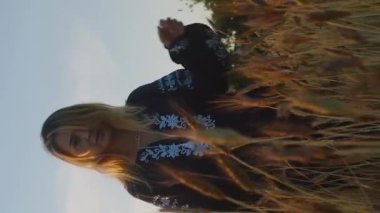 Buğday tarlasında dikilen nakışlı romantik kadının dikey portresi.
