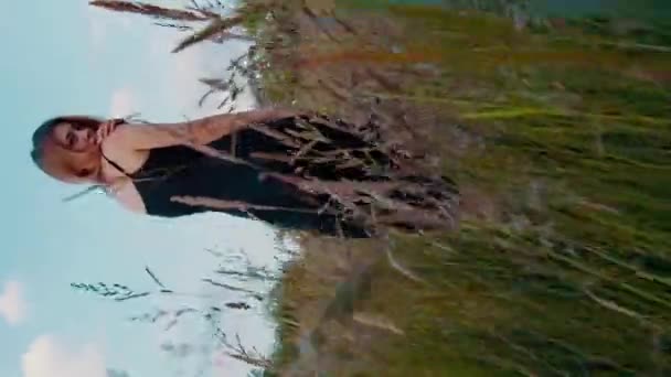 一个穿着连衣裙的浪漫女孩走在一片茂密的草地上 垂直的摄像机正在追赶她 — 图库视频影像
