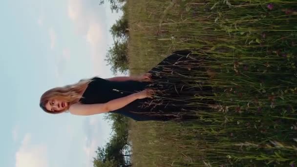 垂直的电影录像浪漫的金发女人穿着黑色衣服在草地上摆姿势 — 图库视频影像