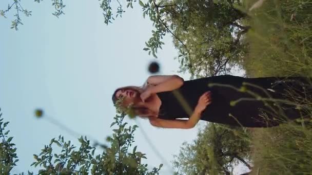 Vertical Vídeo Cinematográfico Hermosa Mujer Rubia Vestido Negro Pie Jardín — Vídeo de stock