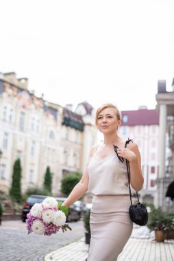 Genç romantik kız ilk buluşmasında bir buket çiçekle şehrin sokaklarında