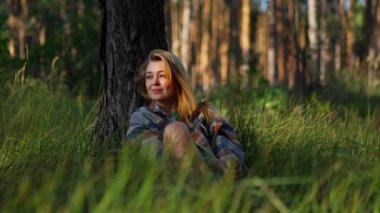 Huzurlu kız dinleniyor ve rahatlıyor. Parktaki çimlerin üzerinde oturuyor. Rahatlama ve meditasyon konsepti.