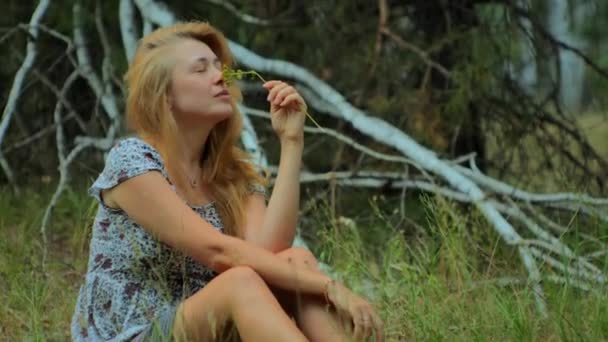 穿着夏装的浪漫姑娘坐在草地上 呼吸着花儿的芬芳 享受着生活 快乐极了 — 图库视频影像