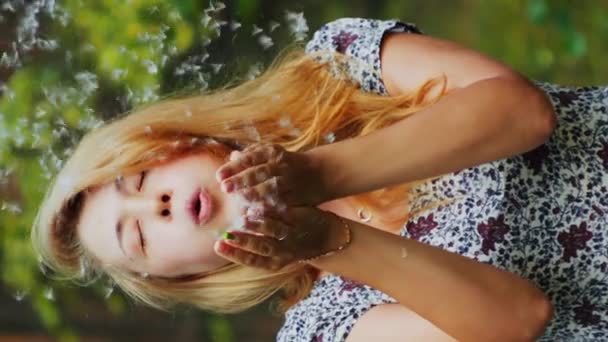 穿着夏装的快乐而浪漫的金发女子的画像 垂直于吹蒲公英种子 — 图库视频影像