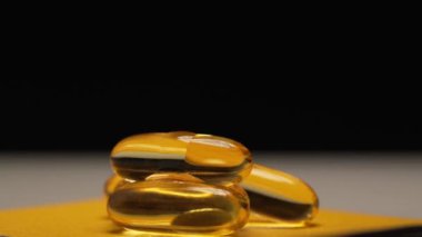 Balık yağı jelatin kapsüllerinden aşağı akıyor. Omega 3 balık yağı hapları.