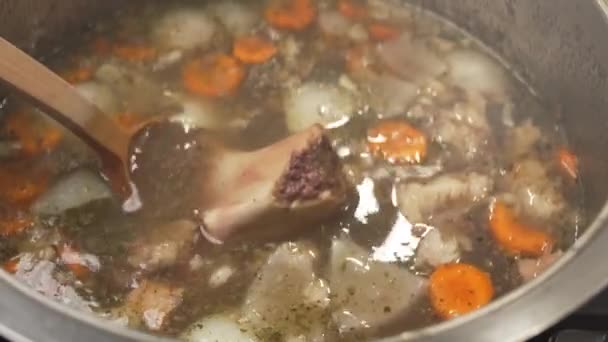 用木制勺子搅拌美味的肉汤 配上胡萝卜和调味品 并配上切碎骨的内部结构 — 图库视频影像
